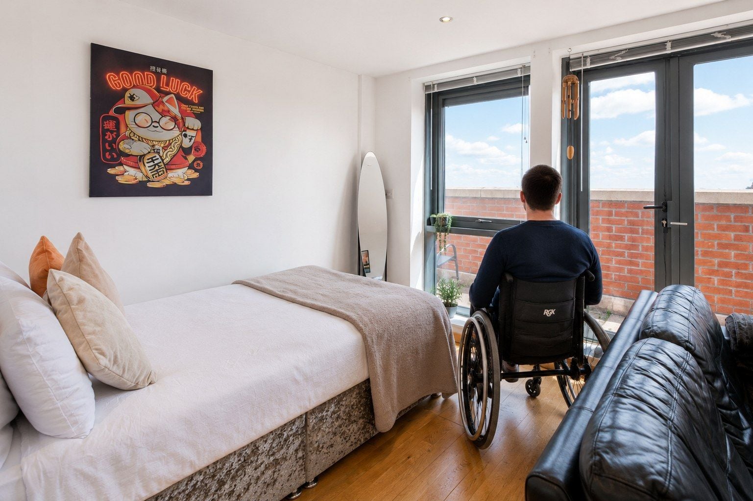 A bedroom with a bed, a wheelchair, a window, and a poster on the wall.