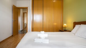 A hotel room with a large wooden wardrobe, a bed with white linens, and a bedside lamp.