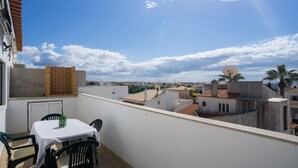 A balcony with a table and chairs, a brick wall, and a view of the cityscape.