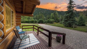Eine Holzterrasse mit Blick auf einen bewaldeten Gebirgszug bei Sonnenuntergang.