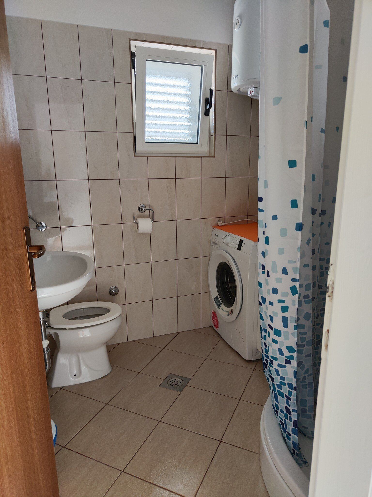 Een kleine badkamer met toilet, wastafel en een wasmachine.