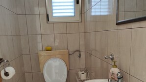 A bathroom with a toilet, sink, and a small window.
