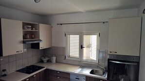 A modern kitchen with a dishwasher, oven, and a window with blinds.