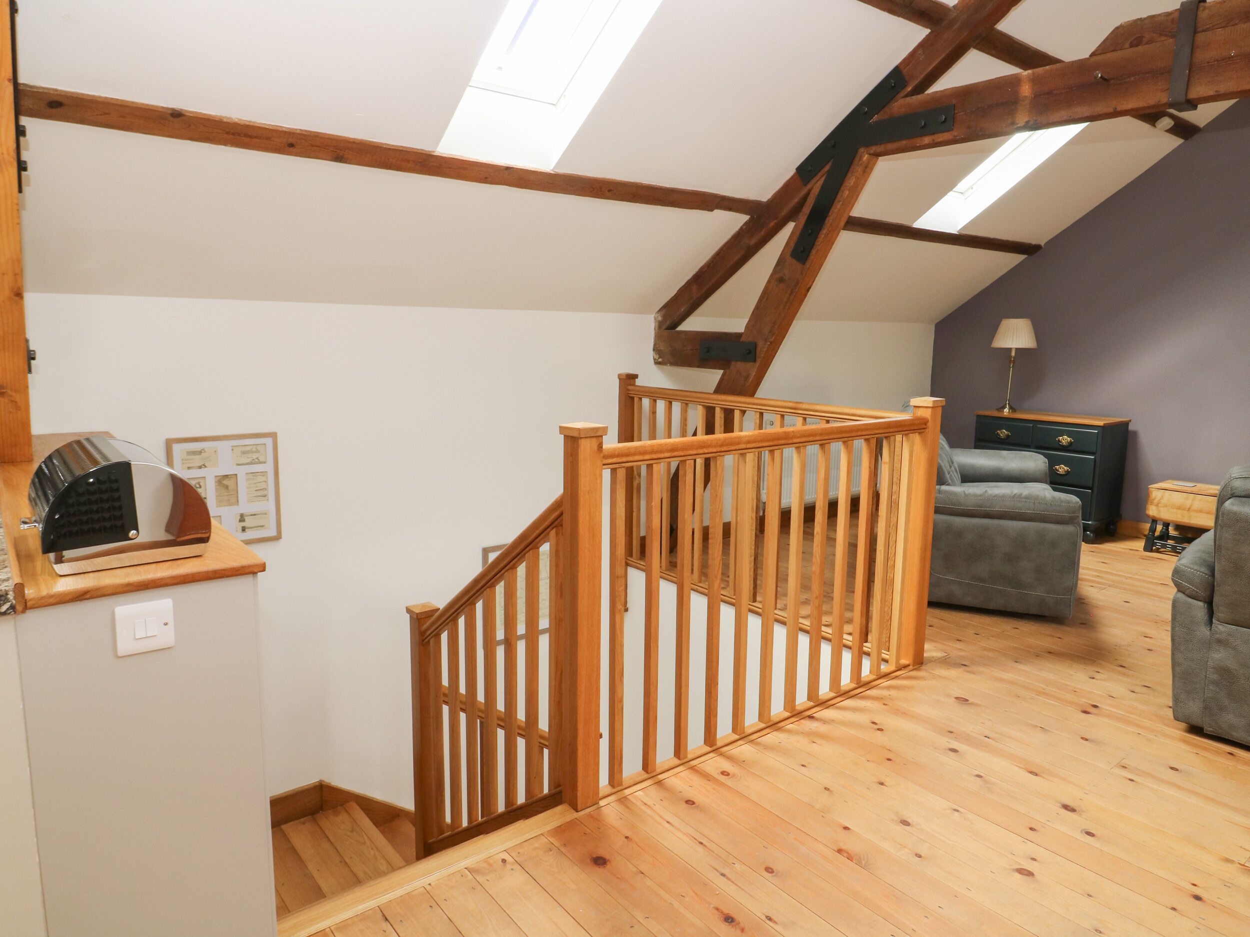 A loft bedroom with a wooden staircase, a sofa, and a lamp.