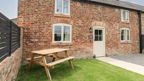 Une petite maison en briques avec une table de pique-nique en bois dans la cour.