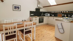 Une cuisine avec une table et des chaises en bois, un four à micro-ondes, un four traditionnel et un évier.