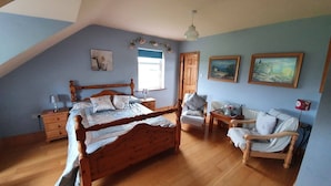 Un dormitorio con una cama y una silla de madera, una mesita pequeña y un radiador.