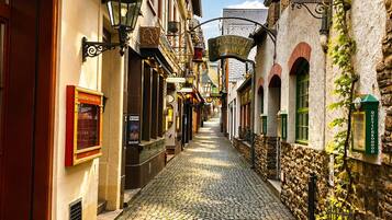 Une rue pavée bordée de bâtiments historiques, dont une enseigne indiquant « International » et « Quetsch Kommöd ».