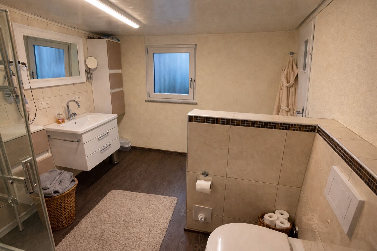 Une salle de bain équipée d’une douche, de toilettes, d’un lavabo et d’un miroir.