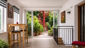 A modern interior with a wooden dining table, chairs, a red spiral staircase, and potted plants.