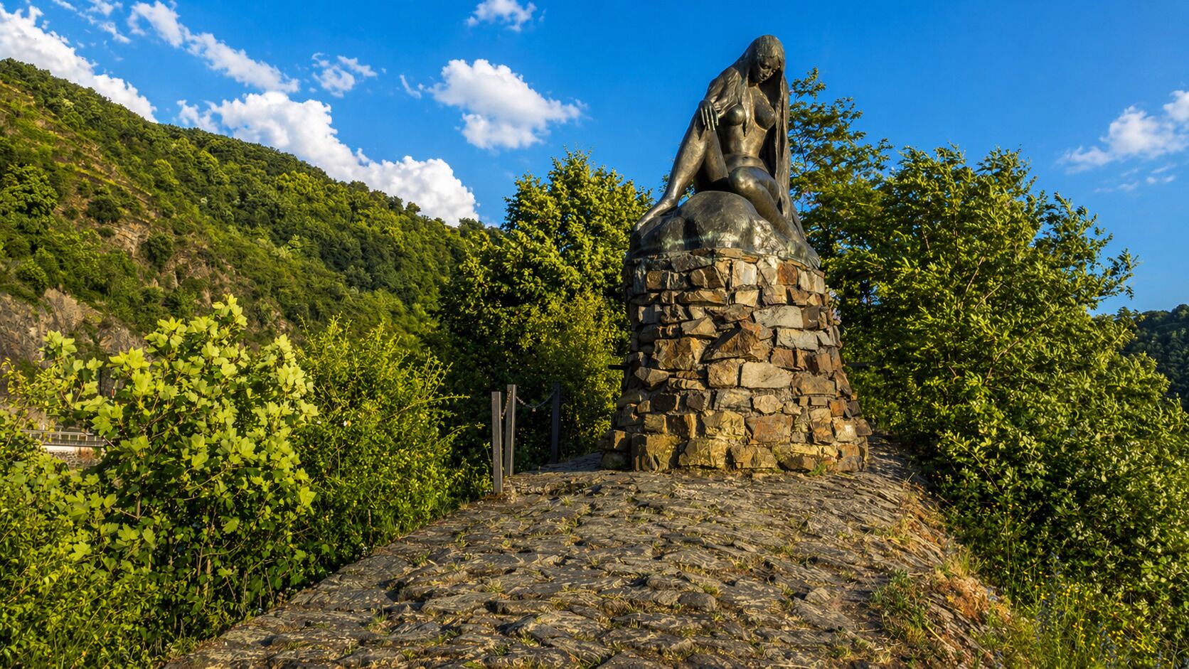 Eine Statue auf einem Steinsockel vor einer Berglandschaft.