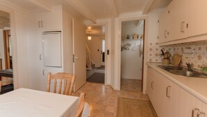 Una cocina compacta con armarios blancos, horno empotrado y un lavabo.