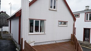 Un edificio blanco con techo rojo y una terraza de madera.