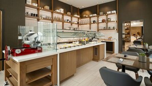 Een modern café met een centraal aanrecht, houten schappen en een zithoek met tafels en stoelen.