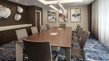 Une salle de conférence avec une longue table, des chaises et des œuvres d’art abstraites accrochées aux murs.