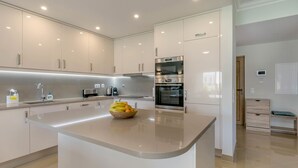 A modern kitchen with a central island, built-in appliances, and a clean, minimalist design. - Casa Makin at Boa Vista Golf Resort, Bayview Village (Lagos)