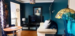 Ett vardagsrum med en soffa, en tv, en lampa och en vas.