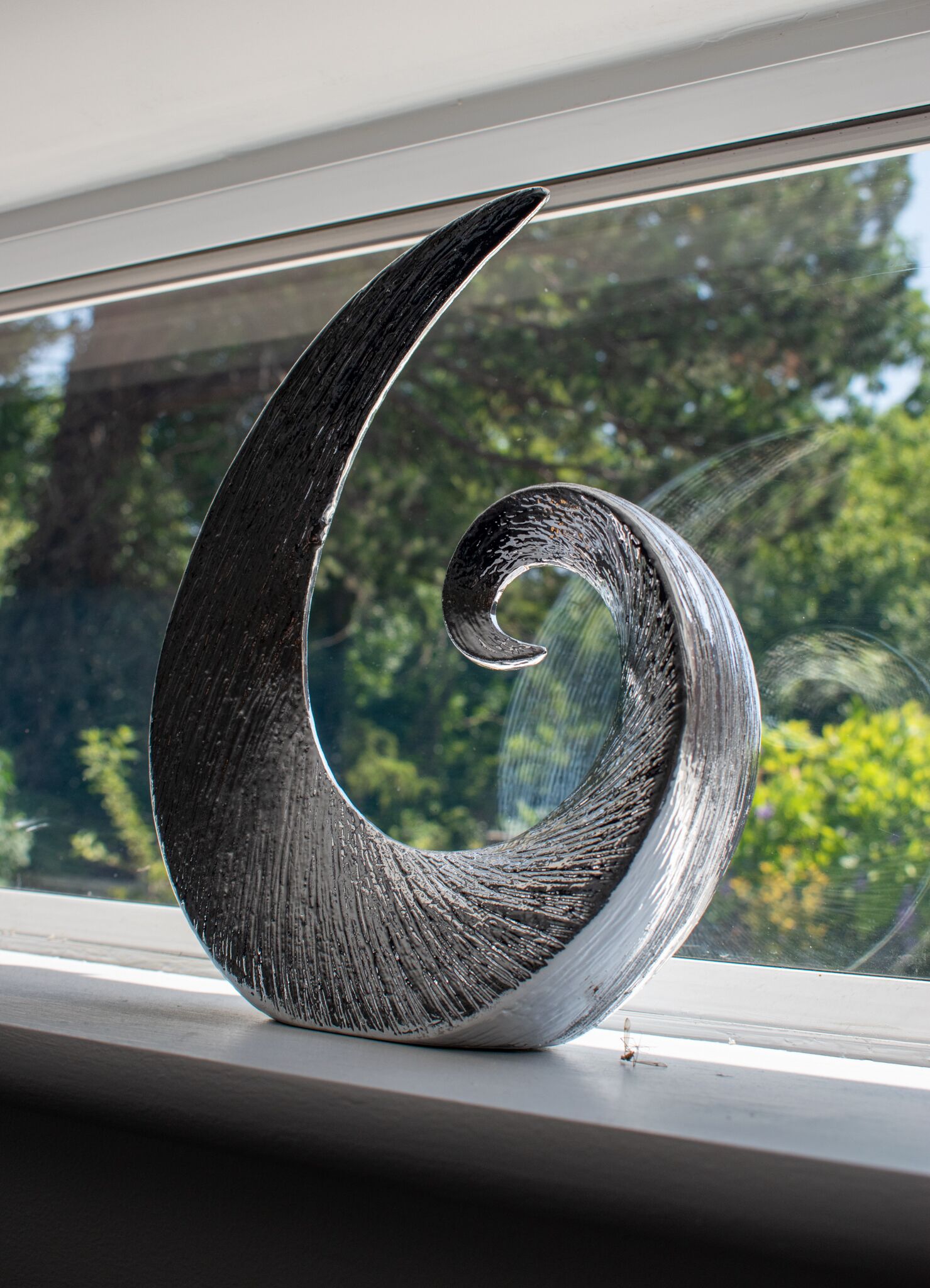 Une sculpture en forme de spirale, posée sur un rebord de fenêtre.