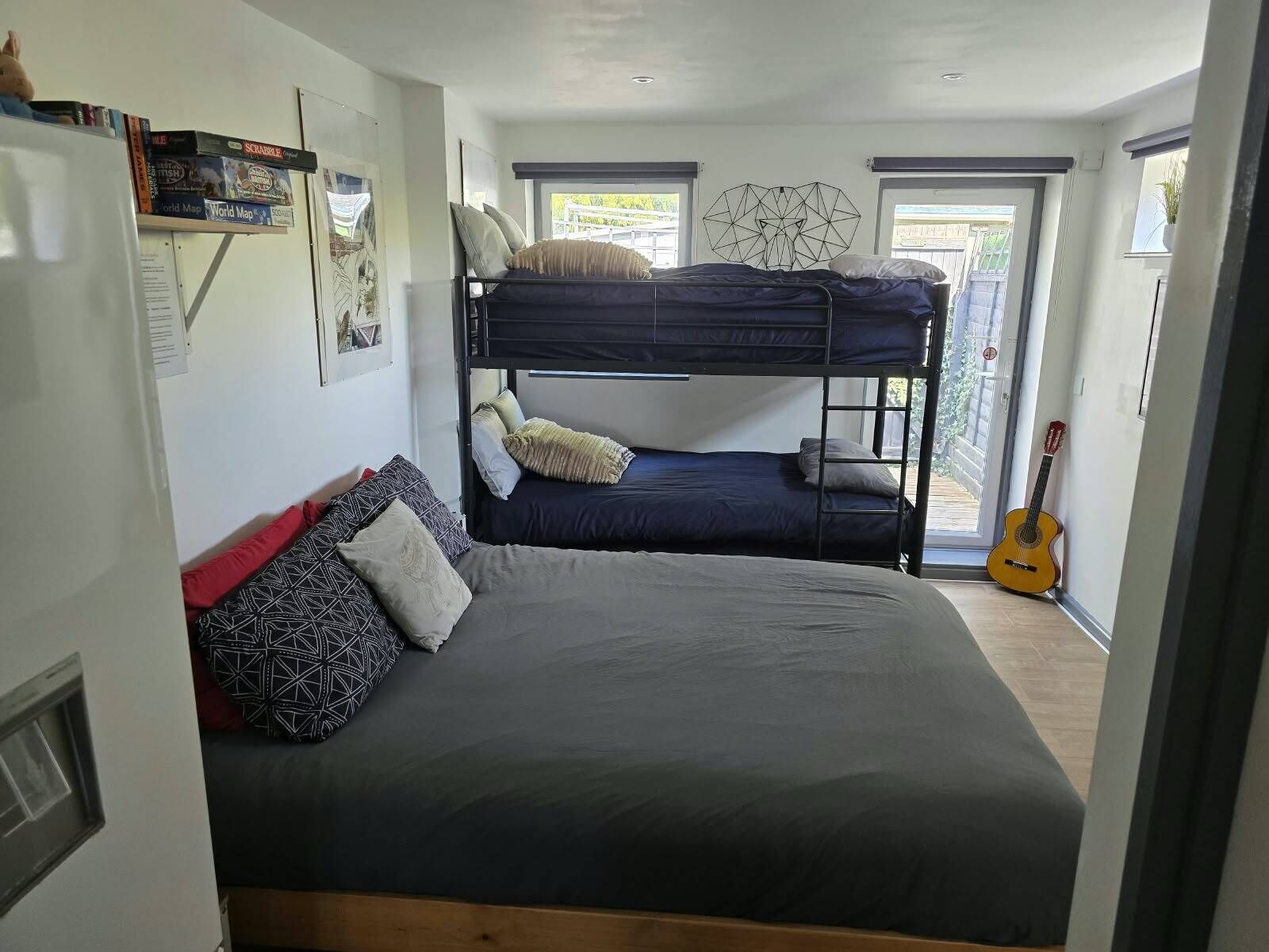 A room with bunk beds, a guitar, and a window with a view.