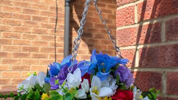 Un cesto appeso con diversi fiori davanti a un muro di mattoni.