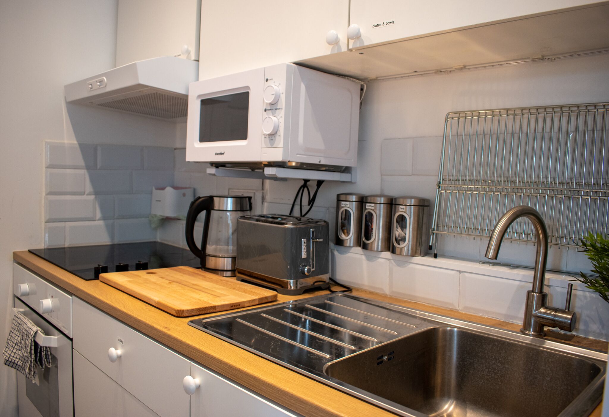A modern kitchen with a built-in microwave, toaster, and stainless steel sink.