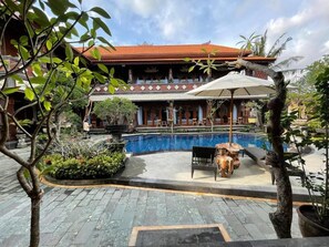 A traditional building with a tiled roof, a swimming pool, and outdoor seating. - Mikuk Cottages Canggu (Canggu)