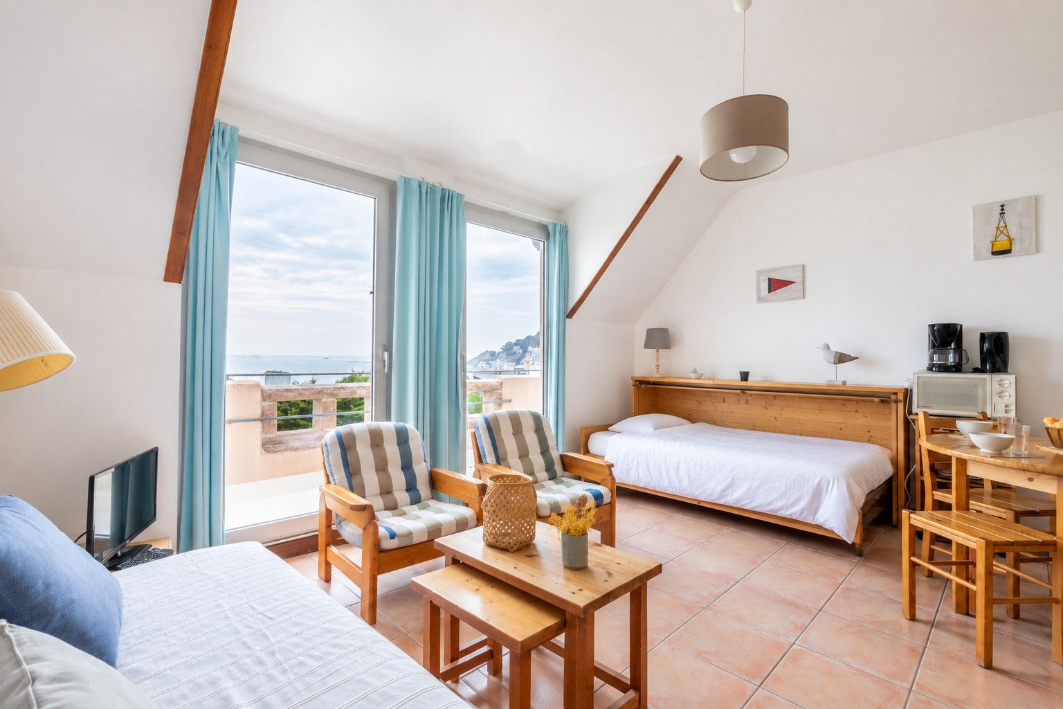Une chambre à coucher avec un lit, un bureau, une chaise et une vue sur la mer.