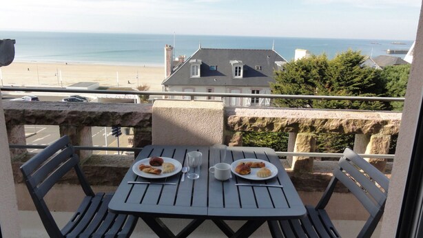 Un balcón con una mesa para dos, con vistas a la playa y al mar.
