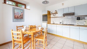 Une cuisine moderne avec des meubles blancs, une table à manger en bois et une affiche ancienne accrochée au mur.
