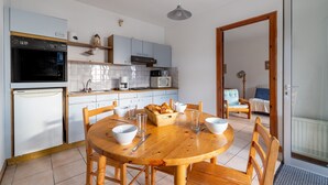Une cuisine compacte avec un coin repas, comprenant une table en bois, des chaises et un petit réfrigérateur.
