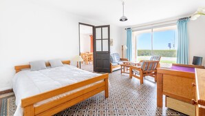 A hotel room with a bed, a desk, and a chair. There is a door leading to a balcony. - Garden level with sea view in the heart of Pléneuf (Pléneuf-Val-André)