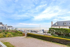 Une vue sur la côte, avec un espace de stationnement, un bâtiment doté d’un balcon et une plage en arrière-plan.