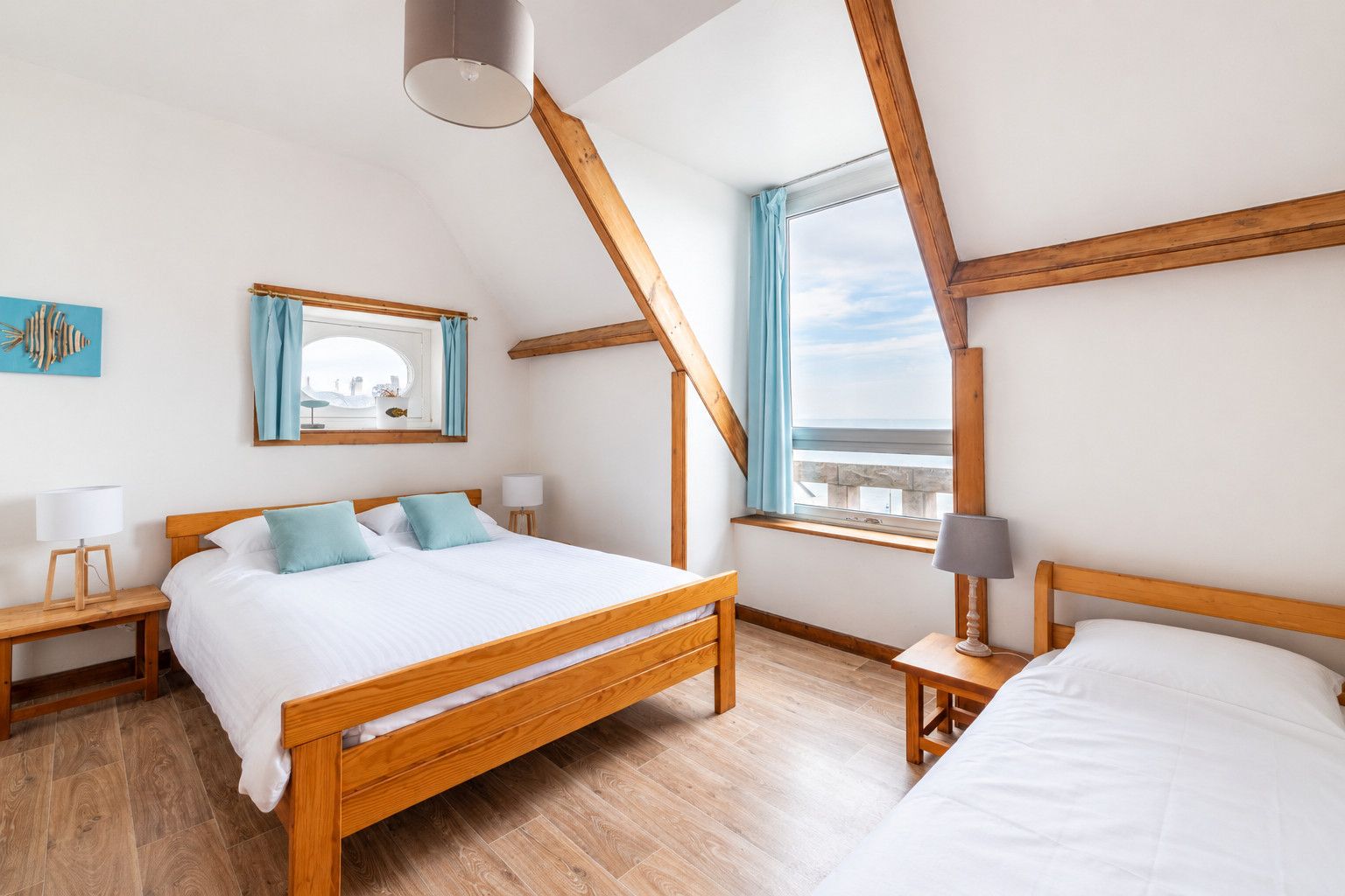 A bedroom with a wooden bed, two bedside tables, a window with curtains, and a view of the sky.