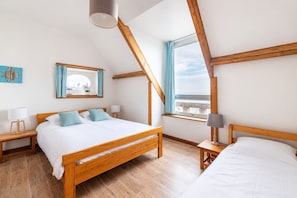 A bedroom with a wooden bed, two bedside tables, a window with curtains, and a view of the sky.