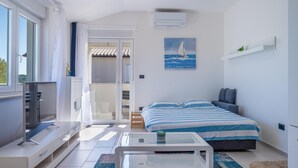 Een moderne slaapkamer met een bed, een televisie, een glazen tafel en uitzicht op het omliggende landschap.