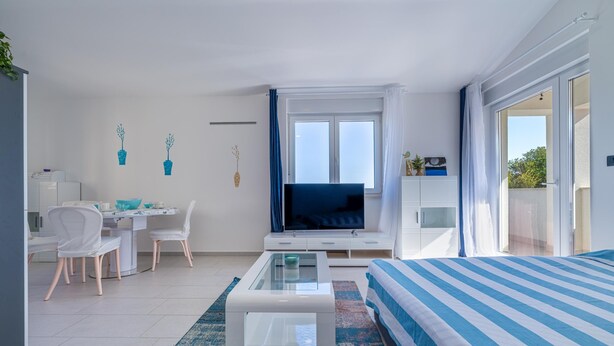 Een moderne hotelkamer met een bed, een televisie, een bureau met stoel en een zithoek.