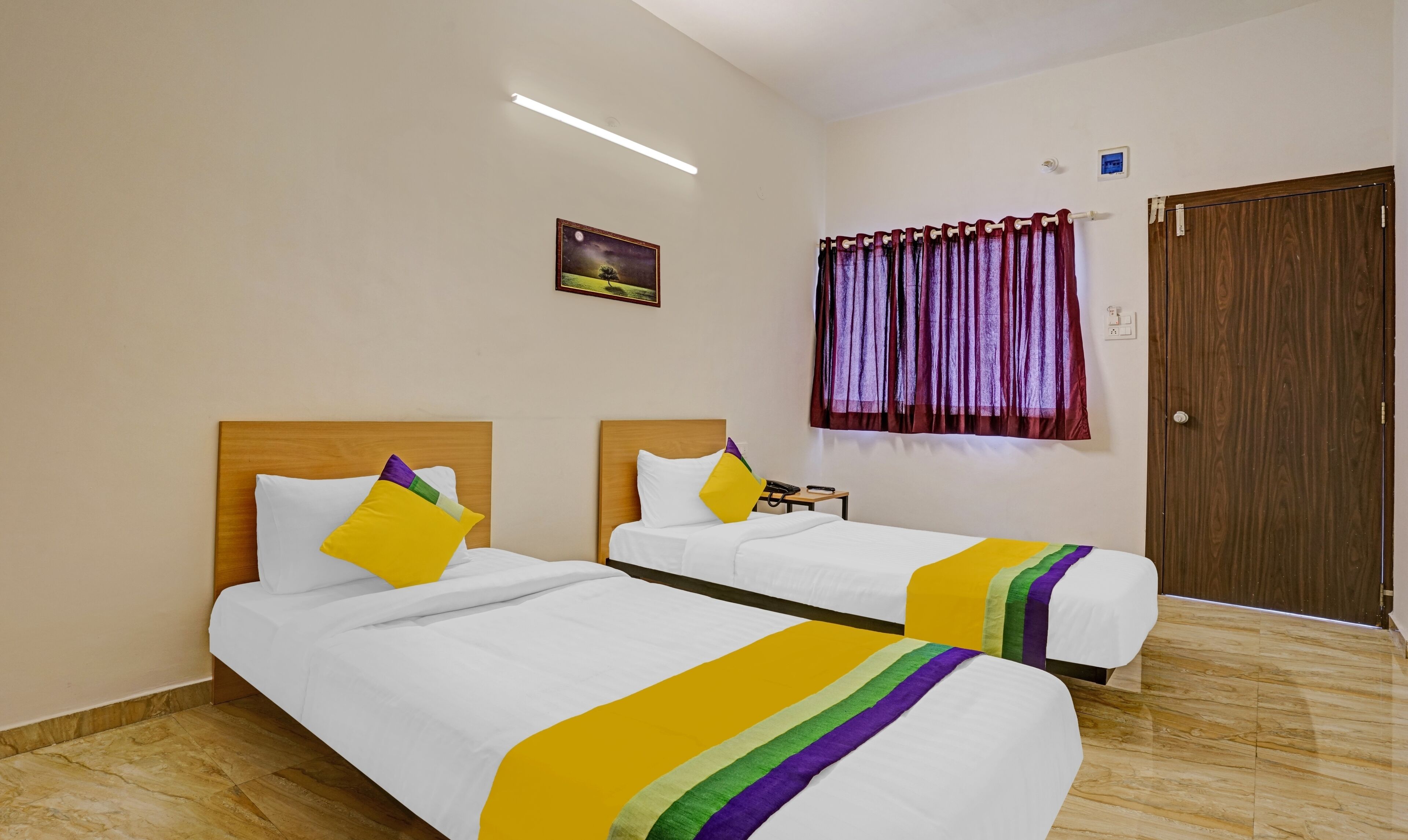 A hotel room with two beds, a nightstand, a painting, a window with curtains, and a wooden door.