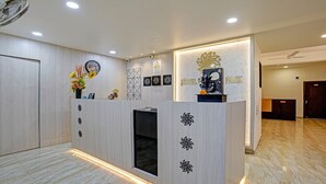 A hotel reception desk with a clock, a notice board, and a flower arrangement. - Itsy Hotels Flowers Park (Nashik)