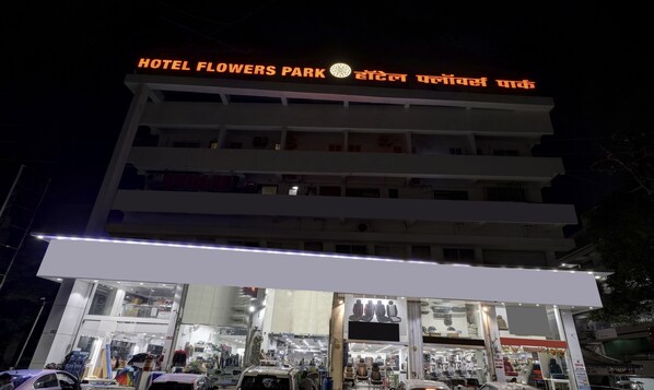 A multi-story building with a sign reading "HOTEL FLOWERS PARK" and another sign in a different language.