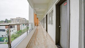 A corridor with a marble floor, metal railings, and a door marked with the number 125. - Itsy Hotels Flowers Park (Nashik)
