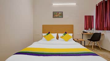 Una habitación de hotel con cama, escritorio, silla y un cuadro en la pared.