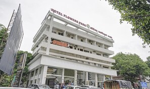 Un hôtel à plusieurs étages, sur lequel on peut lire l’inscription « Hôtel Flowers Park ».