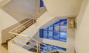 A modern hotel interior with a staircase, a sign indicating the 3rd floor, and a view of the hotel exterior through large windows.