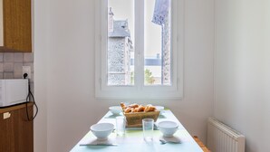 A kitchen with a window, a table with a striped tablecloth, and a box of bread. - Breathtaking view of the sea for 7 people in Pléneuf (Pléneuf-Val-André)