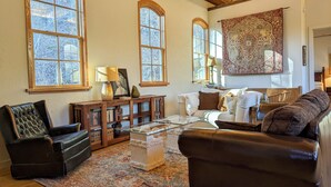 Un salón comedor amplio con ventanas grandes, una chimenea y un tapiz grande.