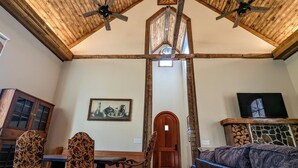 Un comedor con techo de madera, un cuadro en la pared, una puerta de madera y una chimenea de piedra.