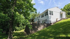 A white single-story house with a front porch, a stone retaining wall, and a staircase leading up to the entrance. - Lakefront for 8, Near KY Speedway, Belterra Casino (Sparta)