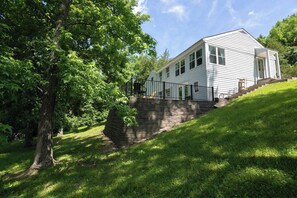 A white single-story house with a front porch, a stone retaining wall, and a staircase leading up to the entrance. - Lakefront for 8, Near KY Speedway, Belterra Casino (Sparta)