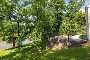 Un jardin avec une terrasse en bois, un étang et une maison.