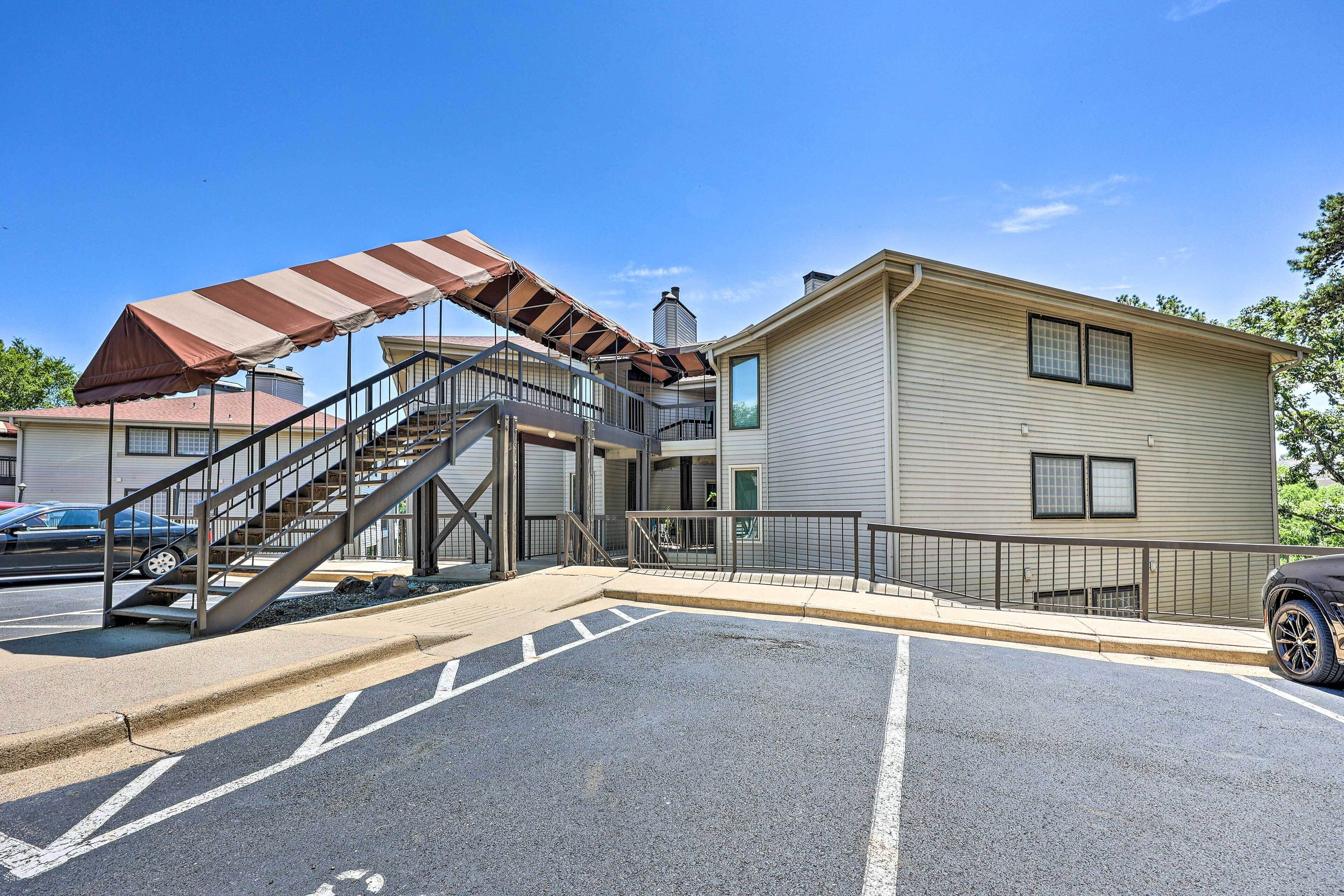 A building with a staircase leading to a second floor, a covered outdoor area, and a parking lot.